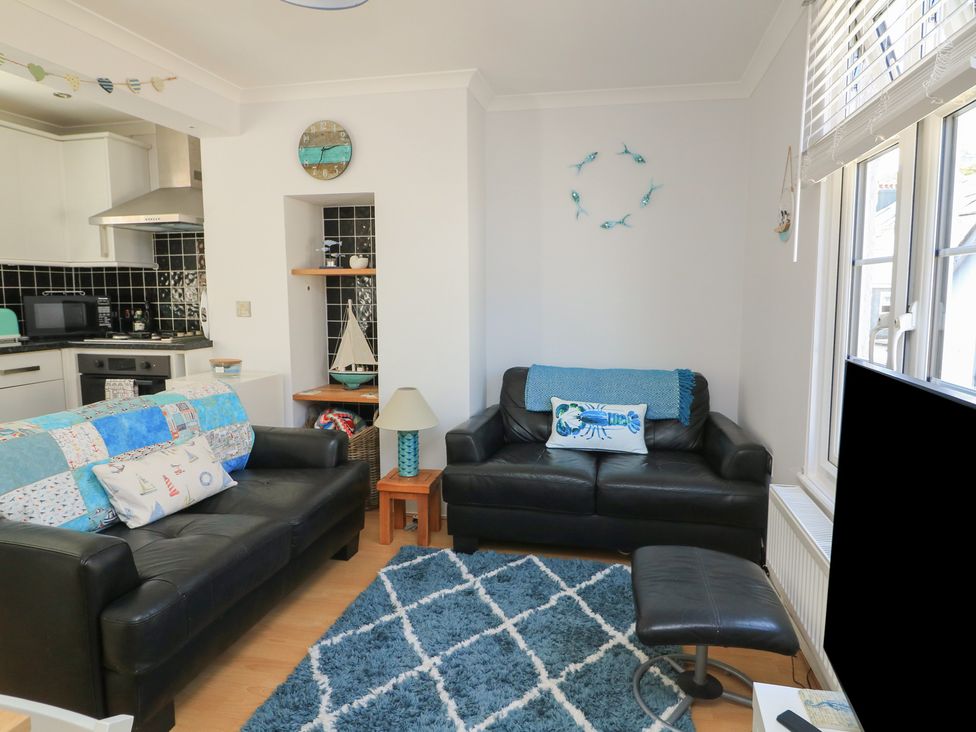 A living room with sofas and kitchen area at The Hideaway in 