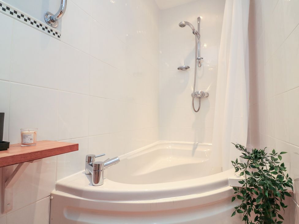 A bathtub with shower head and shelf in a bathroom at The Hideaway