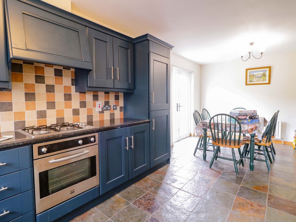 A kitchen with a gas stove and dining table at 7 Killybrack Glen in Omagh