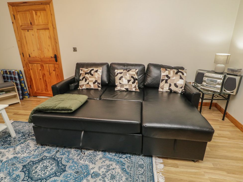 A living room with a black sofa and pillows at The Sperrin Getaway in Omagh