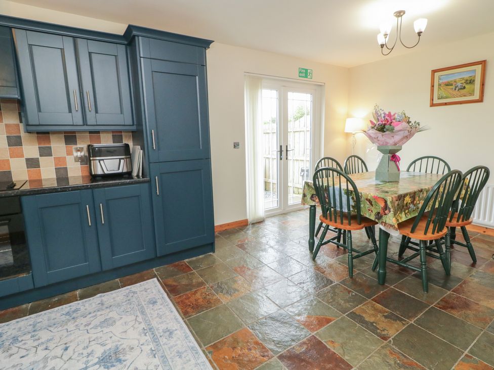 A dining room with a table and chairs and kitchen appliances at The Sperrin Getaway in Omagh