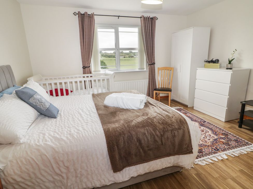 A bedroom with a bed, crib, chair, and dresser at The Sperrin Getaway in Omagh