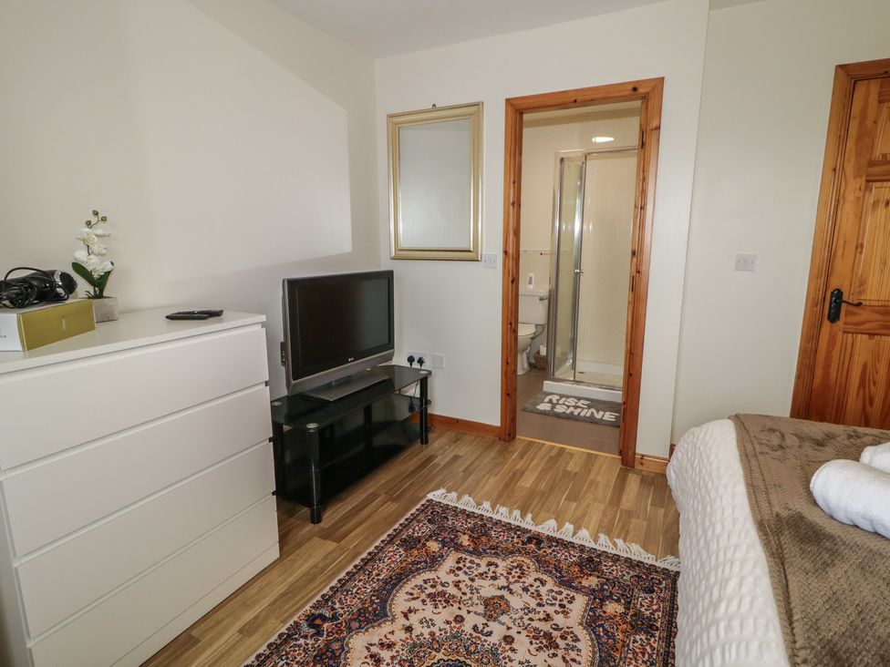A bedroom with a television, dresser, and bathroom entrance at The Sperrin Getaway in Omagh
