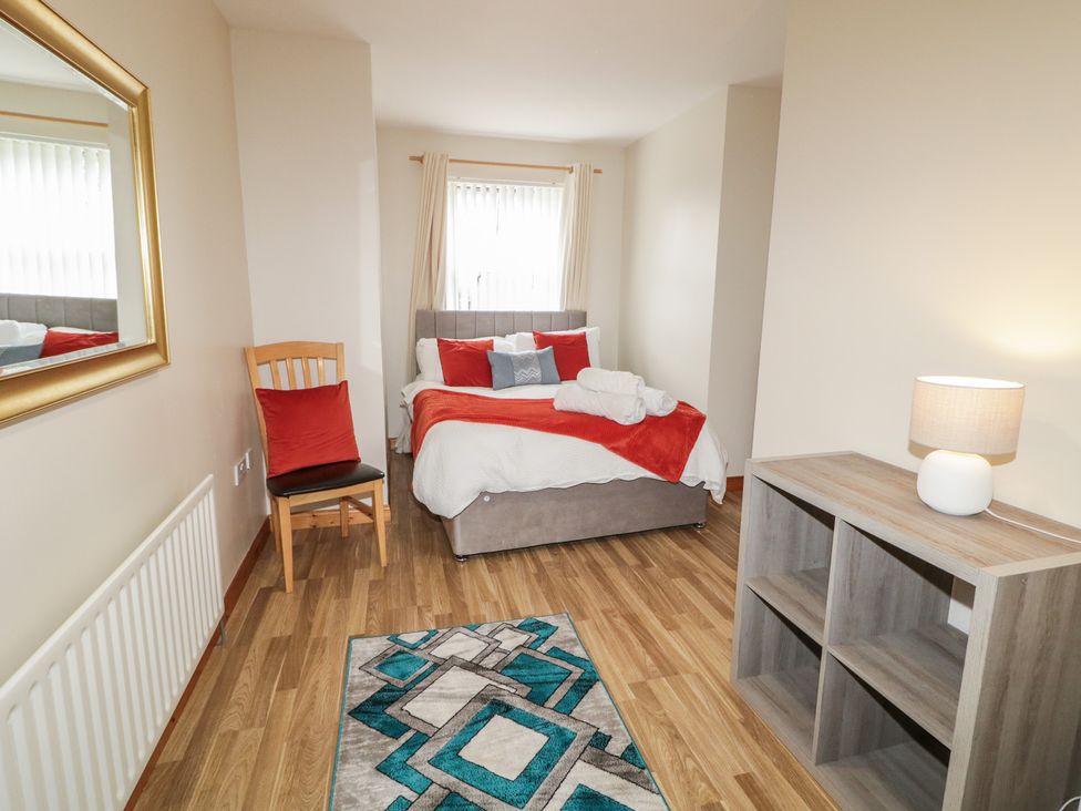 A bedroom with a bed, chair, lamp, and rug at The Sperrin Getaway in Omagh