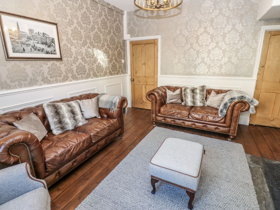 A living room with two brown sofas and an ottoman at 26 Frenchgate in Richmond