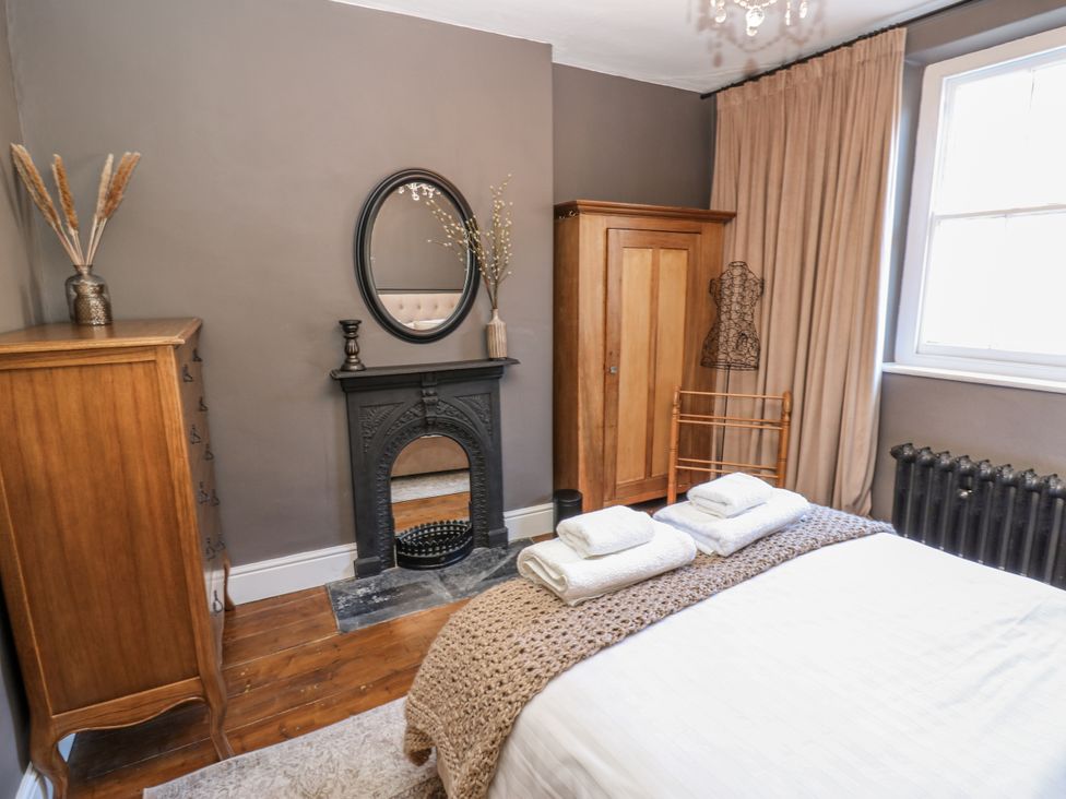 A bedroom with a bed, wardrobe, and fireplace at 26 Frenchgate in Richmond
