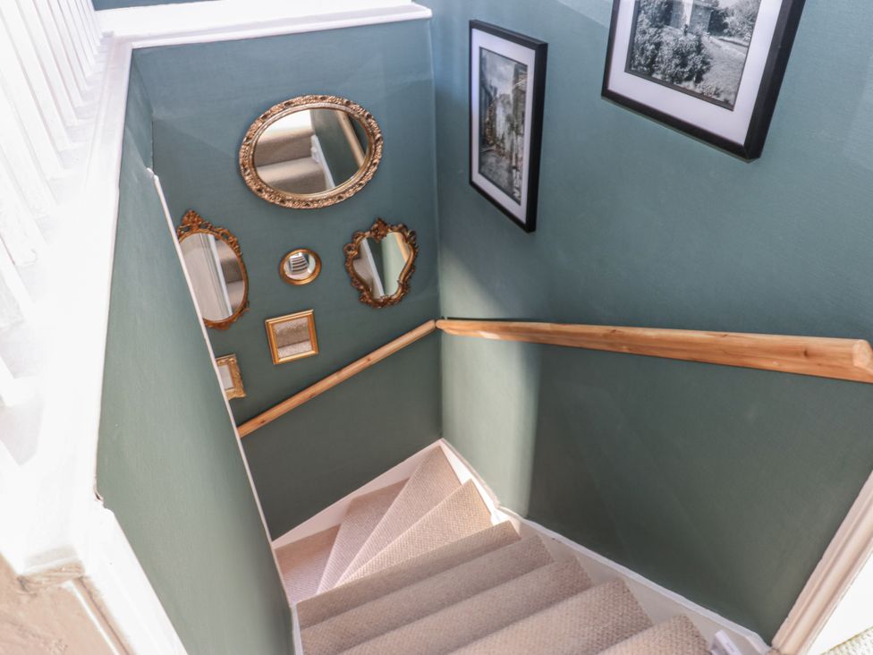 A staircase with mirrors and photographs on the wall at 26 Frenchgate in Richmond