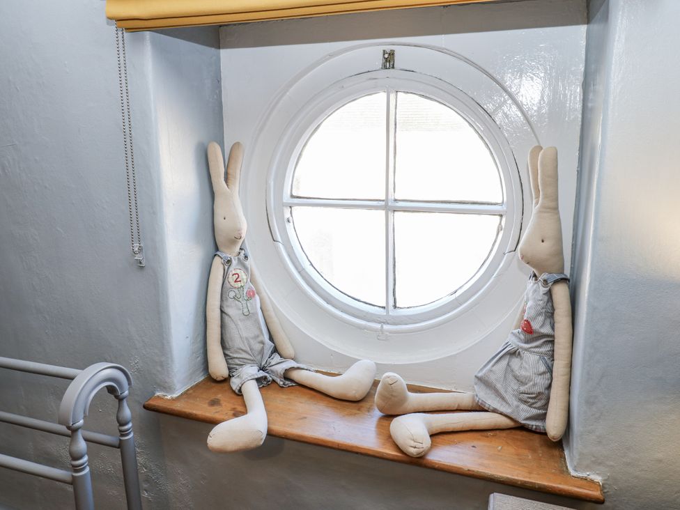 A children's room with dolls on a shelf near a round window at 26 Frenchgate in Richmond