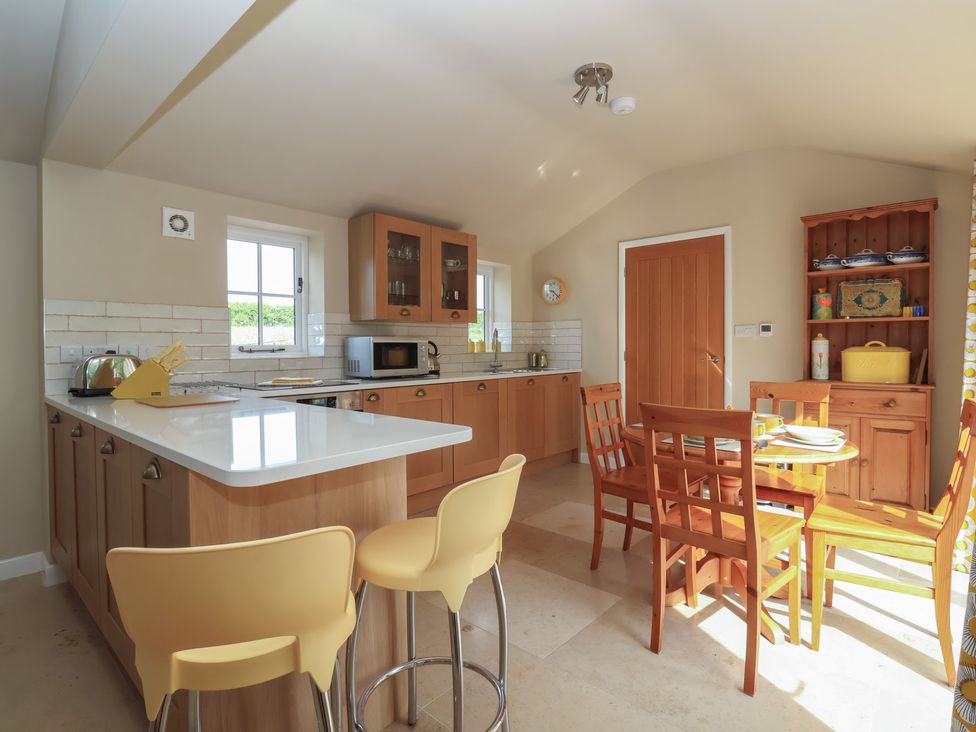 A kitchen with cabinets, microwave, and dining area at Apple Tree Cottage in York