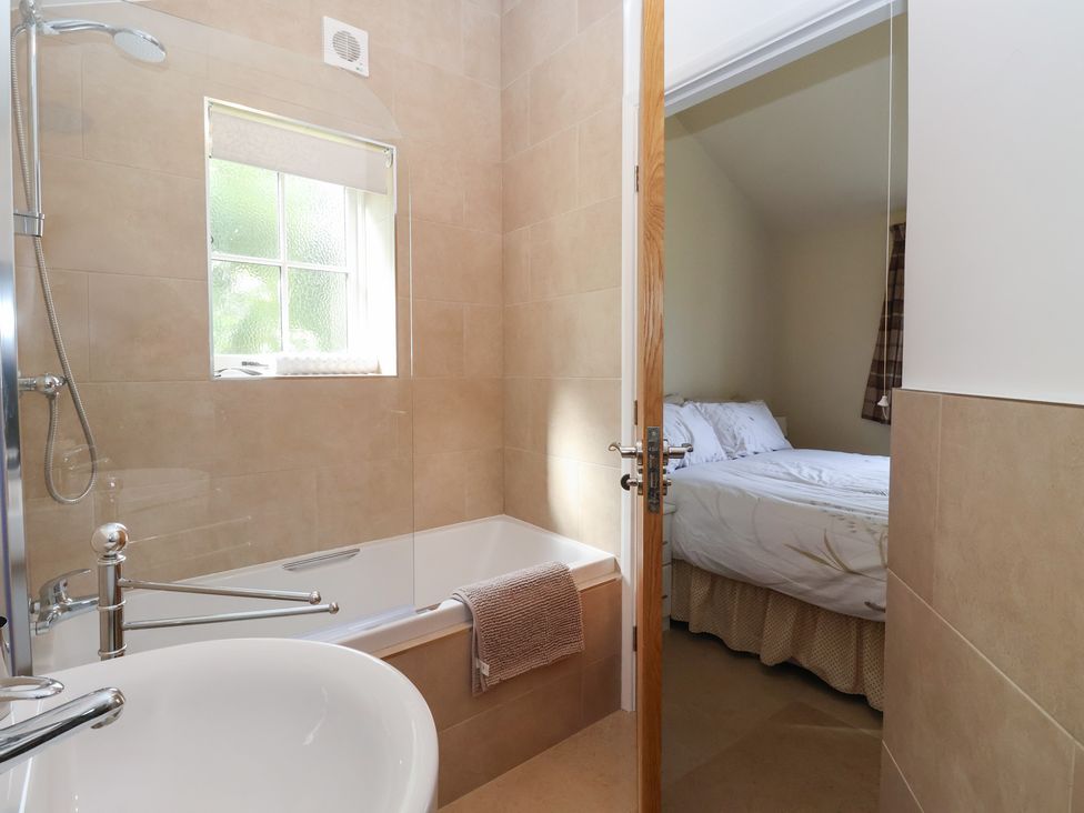 A bathroom with a bathtub and a shower and a view of a bedroom at Apple Tree Cottage in York