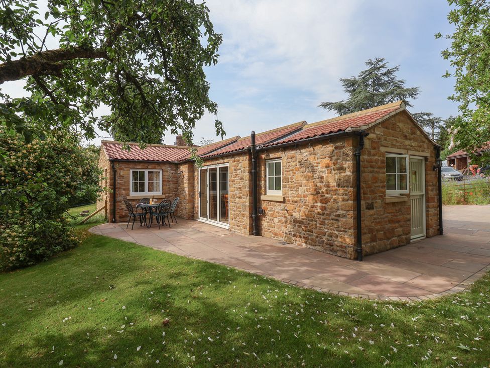A stone cottage with a patio and seating at Apple Tree Cottage in York