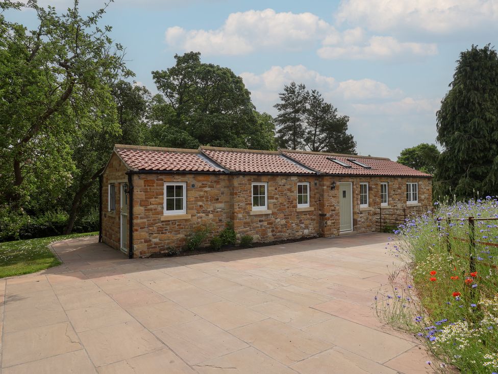A stone cottage with windows and a flower bed at Apple Tree Cottage in York