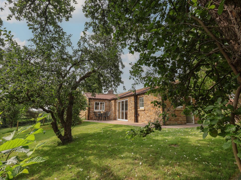 A garden with a table and chairs next to a house at Apple Tree Cottage in York