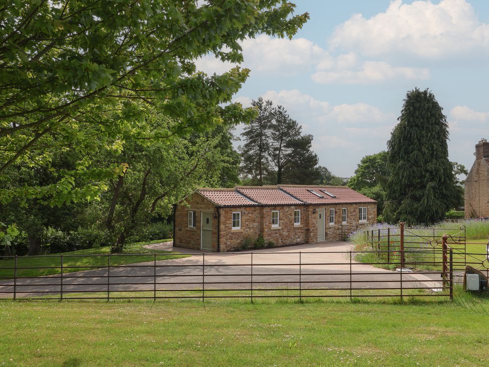 A house with surrounding trees and a fence at Apple Tree Cottage in York
