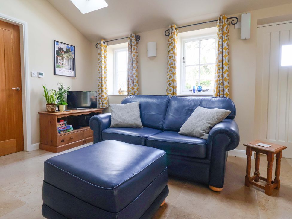 A living room with a blue sofa and a television at Apple Tree Cottage in York