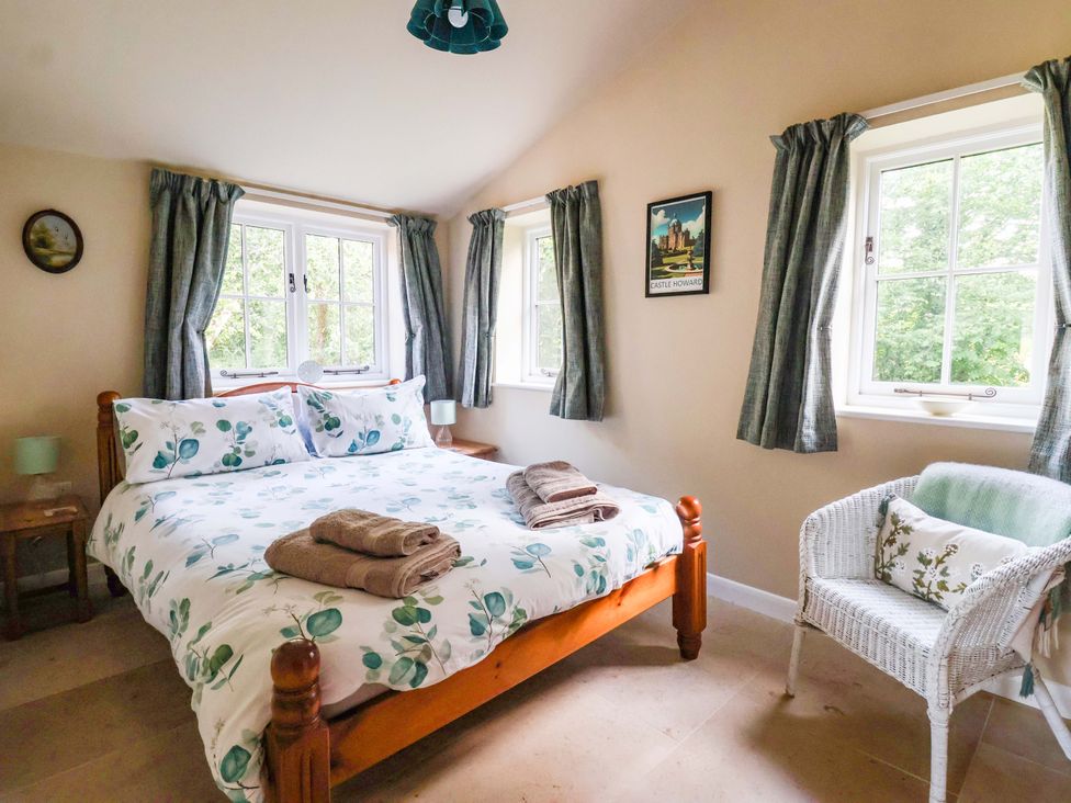 A bedroom with a bed and armchair at Apple Tree Cottage in York