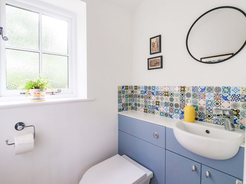 A bathroom with a sink, toilet, and patterned wall tiles at Apple Tree Cottage in York