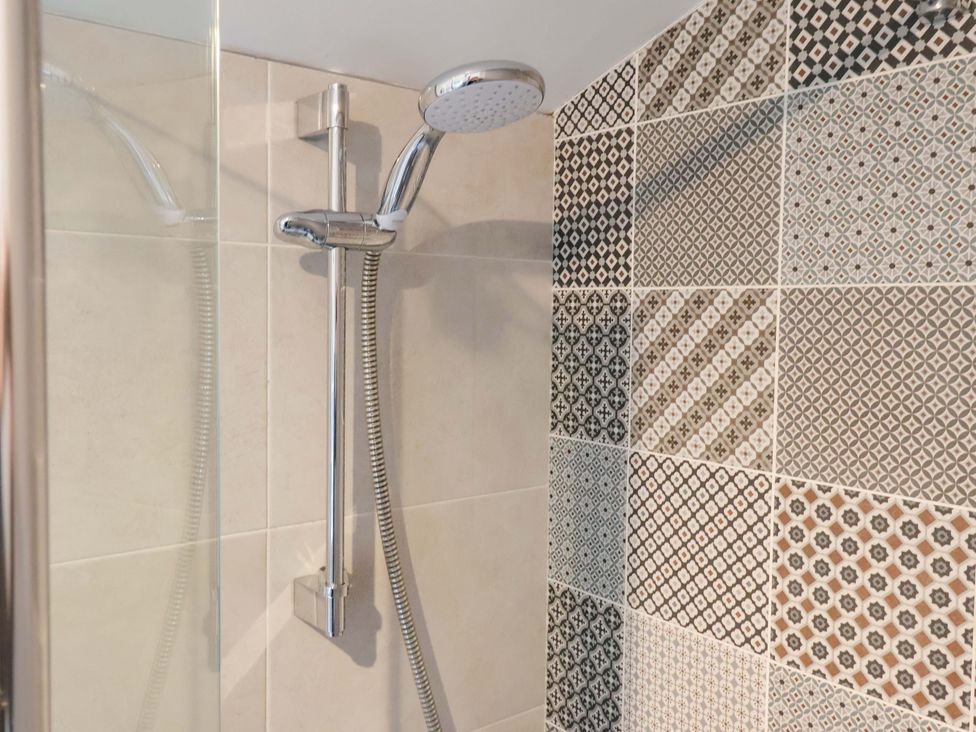 A shower with a wall of patterned tiles at Apple Tree Cottage, York