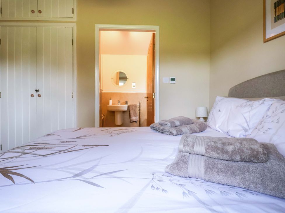 A bedroom with a bed and towels, bathroom visible at Apple Tree Cottage in York