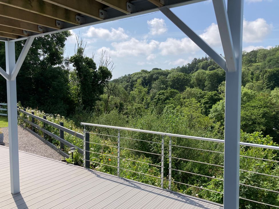 A deck with a railing overlooking trees and grass at 1 Bryn Beudy Narberth