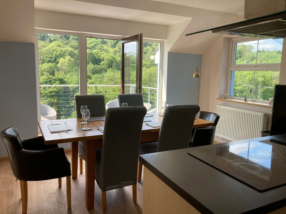 A dining room with a table and chairs overlooking trees at 1 Bryn Beudy in Narberth