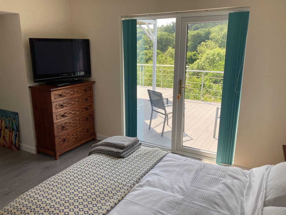 A bedroom with a television and door leading to an outdoor patio at 1 Bryn Beudy in Narberth