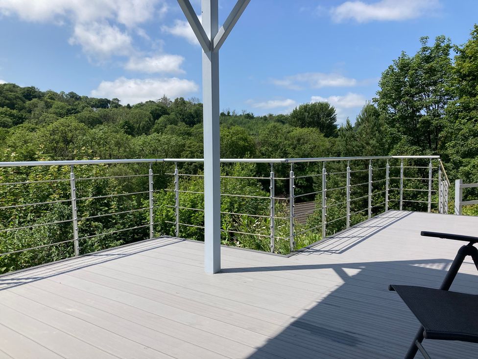 A deck with a railing overlooking a forest at 1 Bryn Beudy Narberth