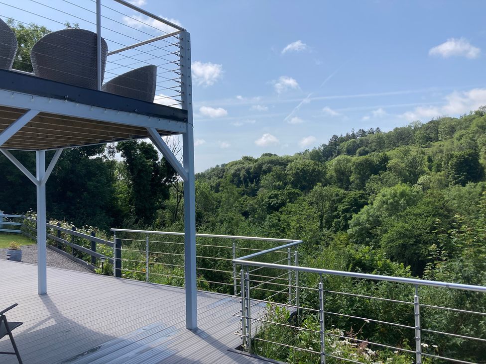 An outdoor deck area with chairs and a view of trees at 1 Bryn Beudy Narberth