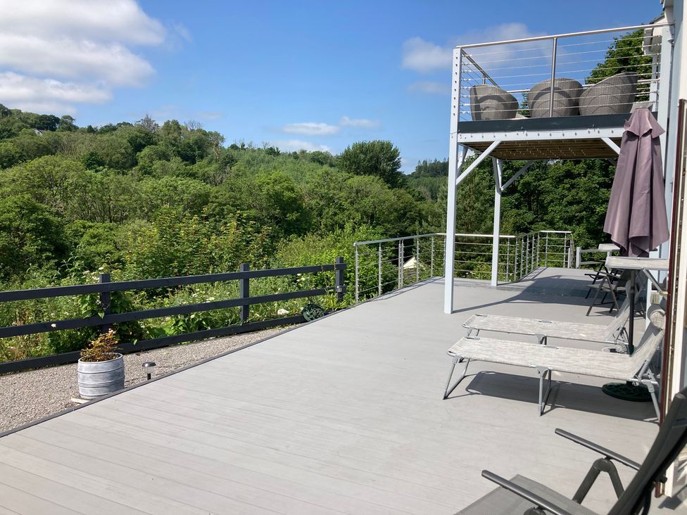 An outdoor area with a deck, chairs and a planter at 1 Bryn Beudy Narberth