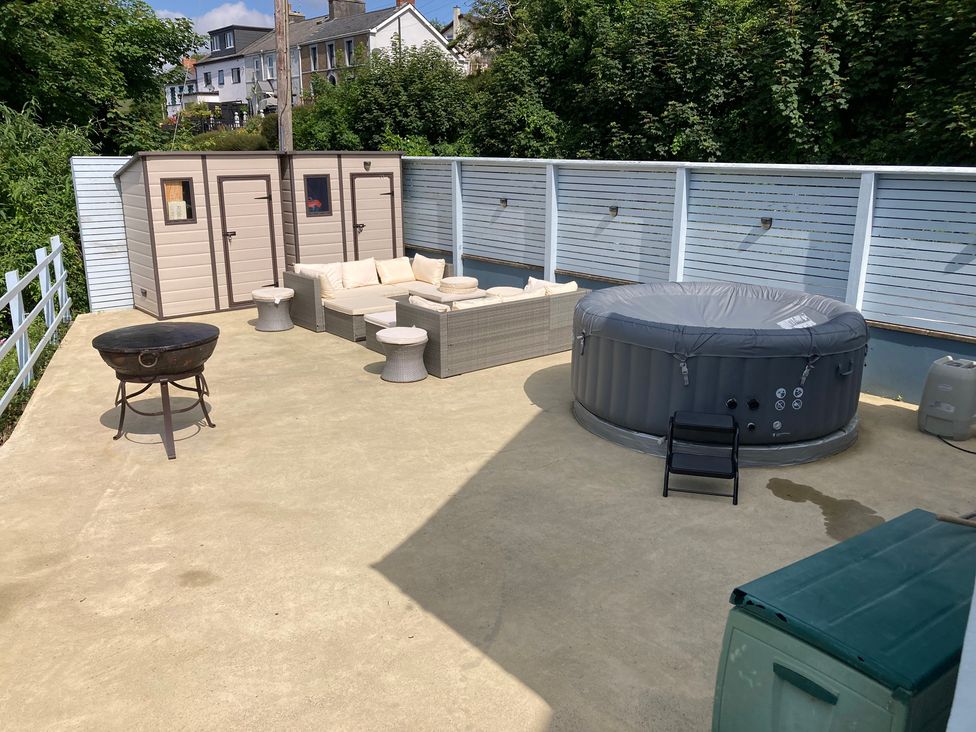 An outdoor area with a hot tub, seating, and storage sheds at 1 Bryn Beudy, Narberth