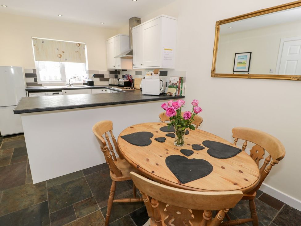 A kitchen with a dining table and chairs at 3 Riverside Bungalows Llanbedr