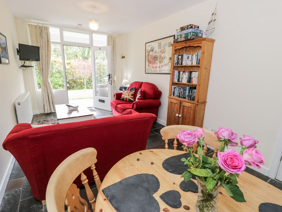 A living room with a red sofa and television at 3 Riverside Bungalows in Llanbedr