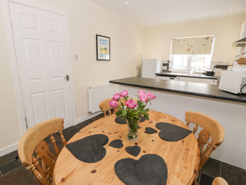 A kitchen with a dining table and flowers at 3 Riverside Bungalows Llanbedr