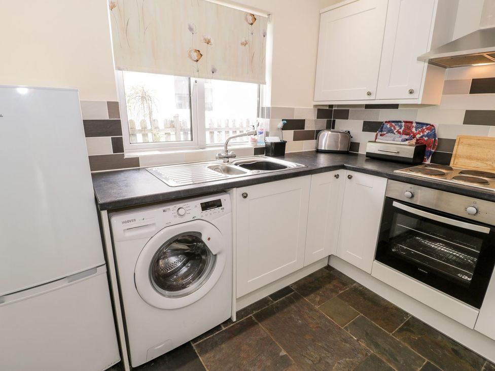A kitchen with appliances including a refrigerator and washing machine at 3 Riverside Bungalows Llanbedr