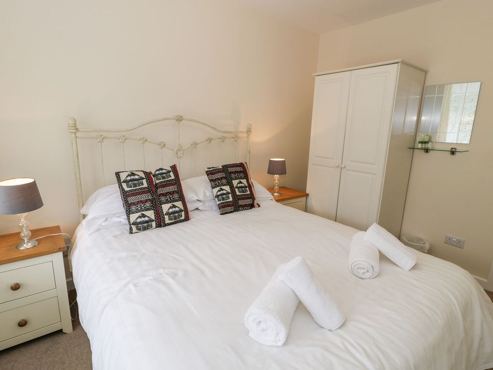 A bedroom with a bed and bedside table at 3 Riverside Bungalows in Llanbedr