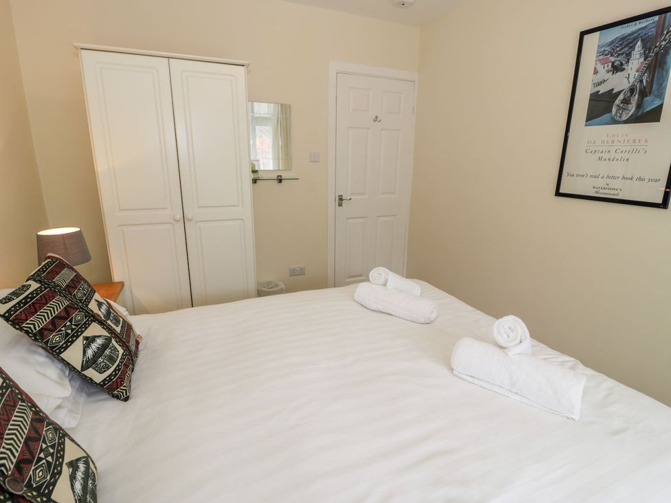 A bedroom with a bed, wardrobe, and lamp at 3 Riverside Bungalows in Llanbedr