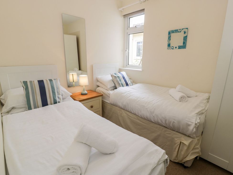 A bedroom with two single beds and a bedside lamp at 3 Riverside Bungalows Llanbedr