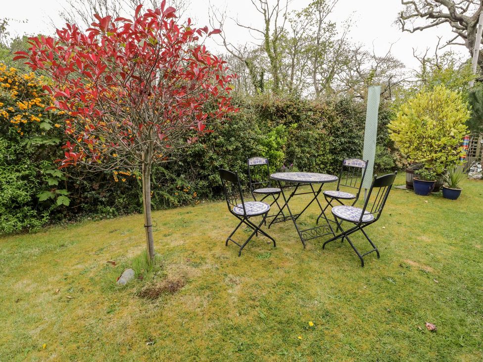 A garden with a table and chairs and a tree at 3 Riverside Bungalows in Llanbedr