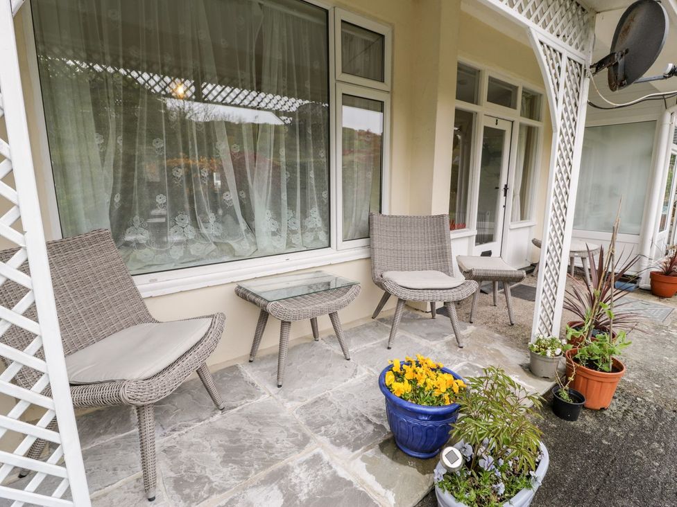 A patio with chairs, a table and planters at 3 Riverside Bungalows Llanbedr