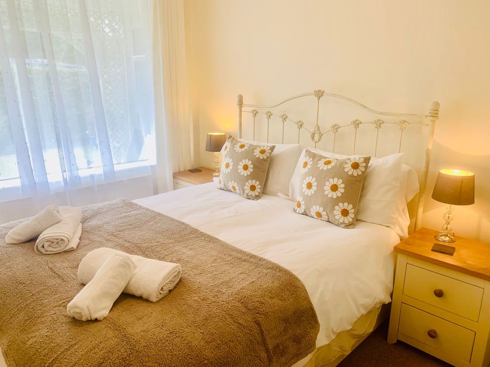 A bedroom with a bed and nightstand at 3 Riverside Bungalows in Llanbedr