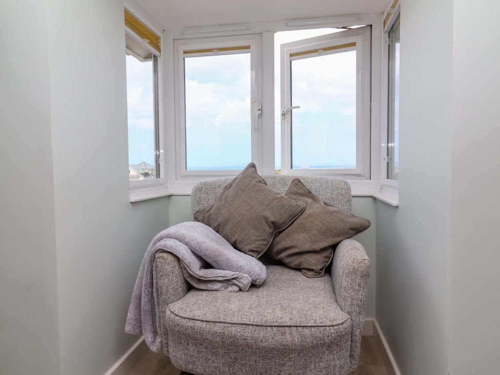 A snug area with an armchair and windows at Sea Sanctuary