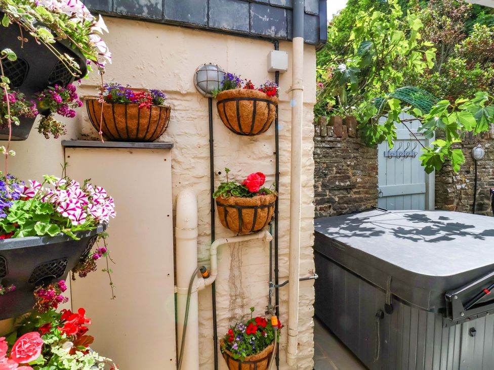 An outdoor area with flower baskets and a hot tub at Sea Sanctuary in 