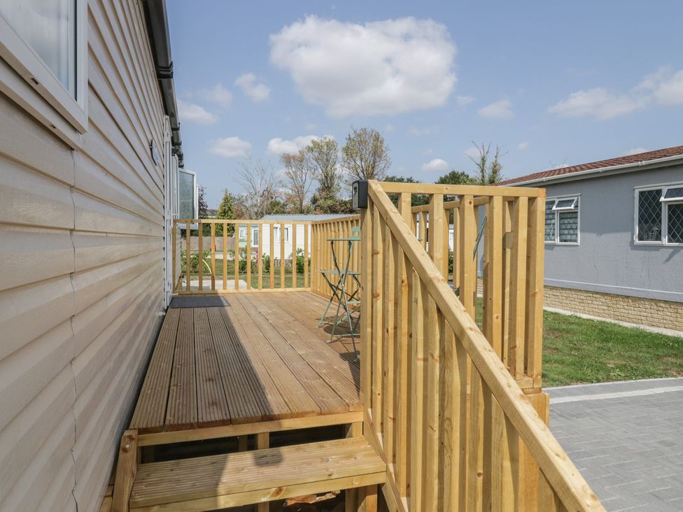 A wooden deck with a chair and railing at Pinewood in Kidlington