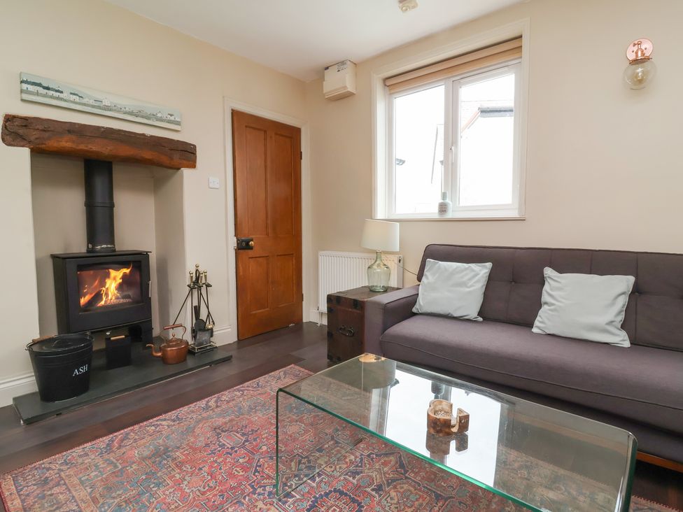 A living room with a fireplace and a sofa at Quay Close Cottage