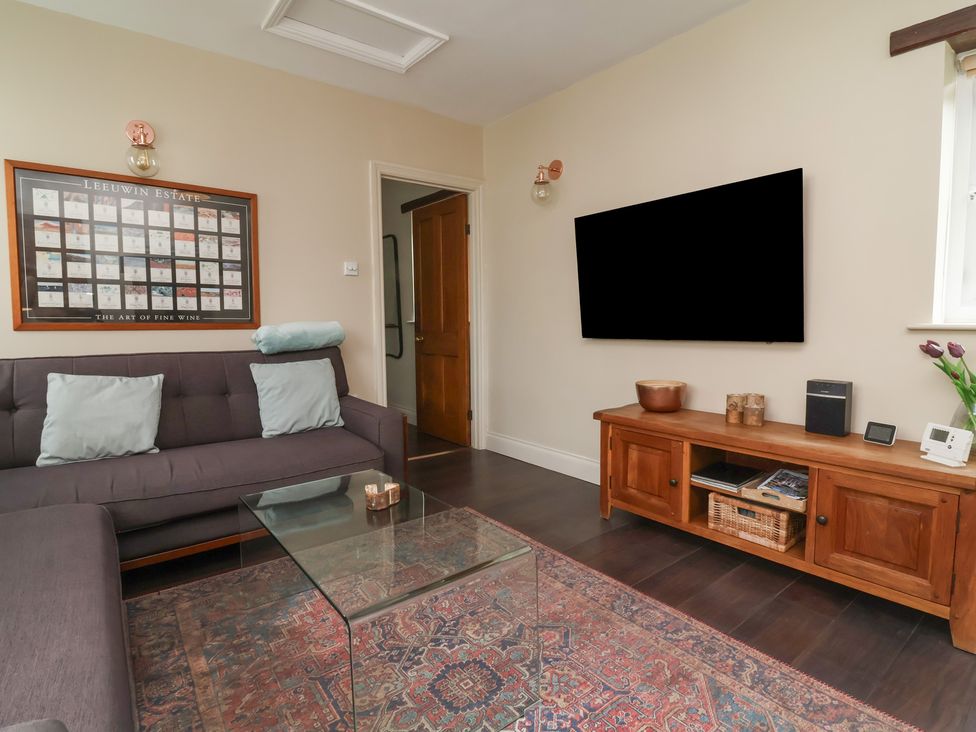 A living room with a sofa and television at Quay Close Cottage