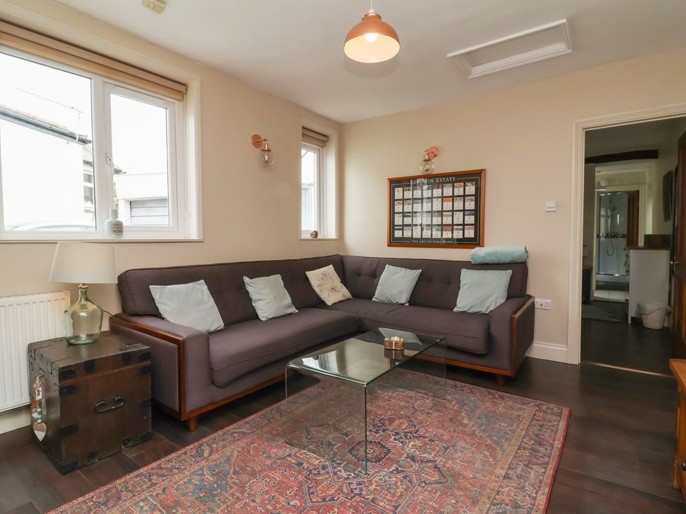 A living room with a sofa and glass table at Quay Close Cottage