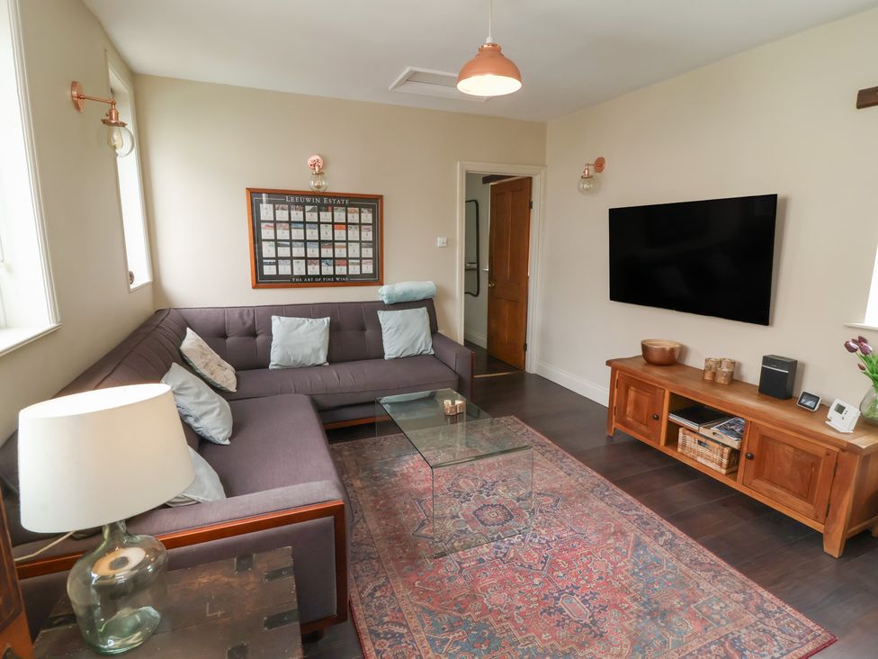 A living room with a sofa and television at Quay Close Cottage 