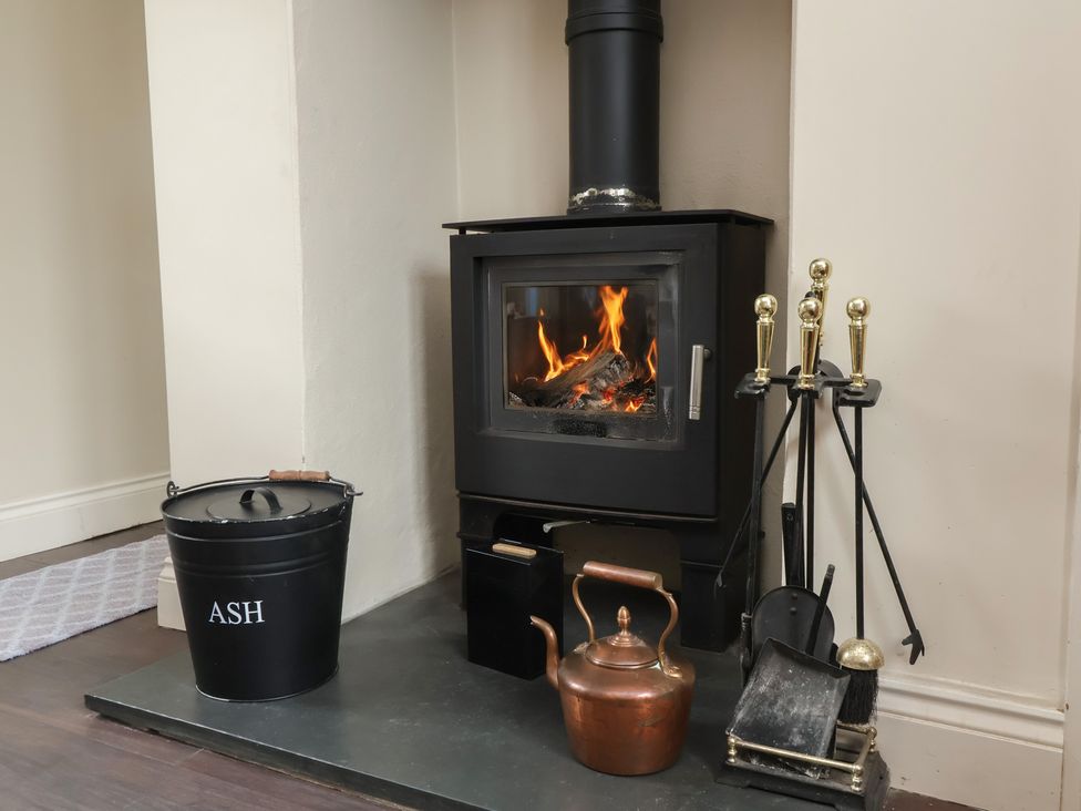 A stove with ash bucket and fireplace tools at Quay Close Cottage