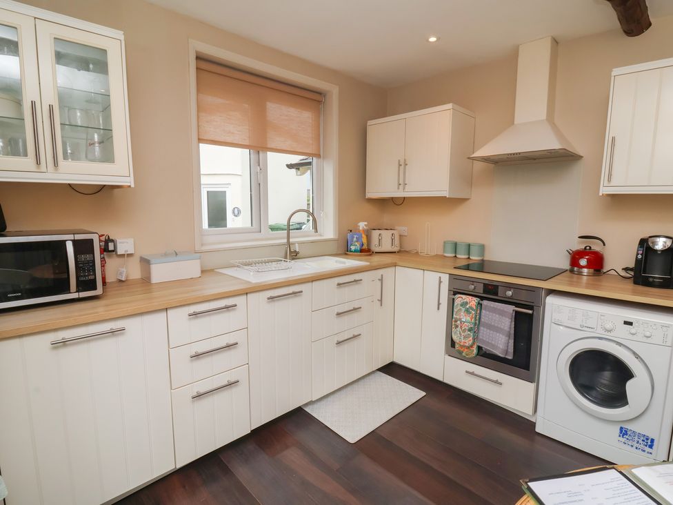A kitchen with cabinets, sink, stove and washing machine at Quay Close Cottage