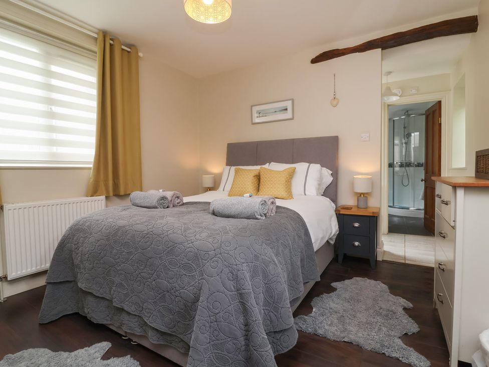 A bedroom with a bed and nightstand at Quay Close Cottage
